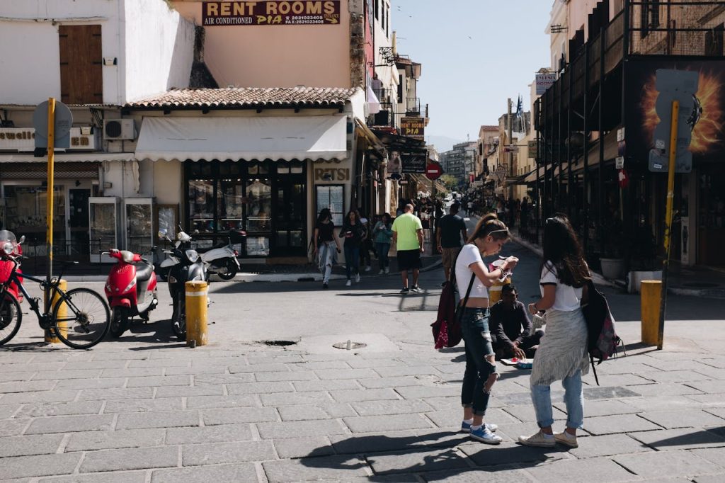 Street view of Chania, Greece featuring people, shops, and urban life under sunny skies.